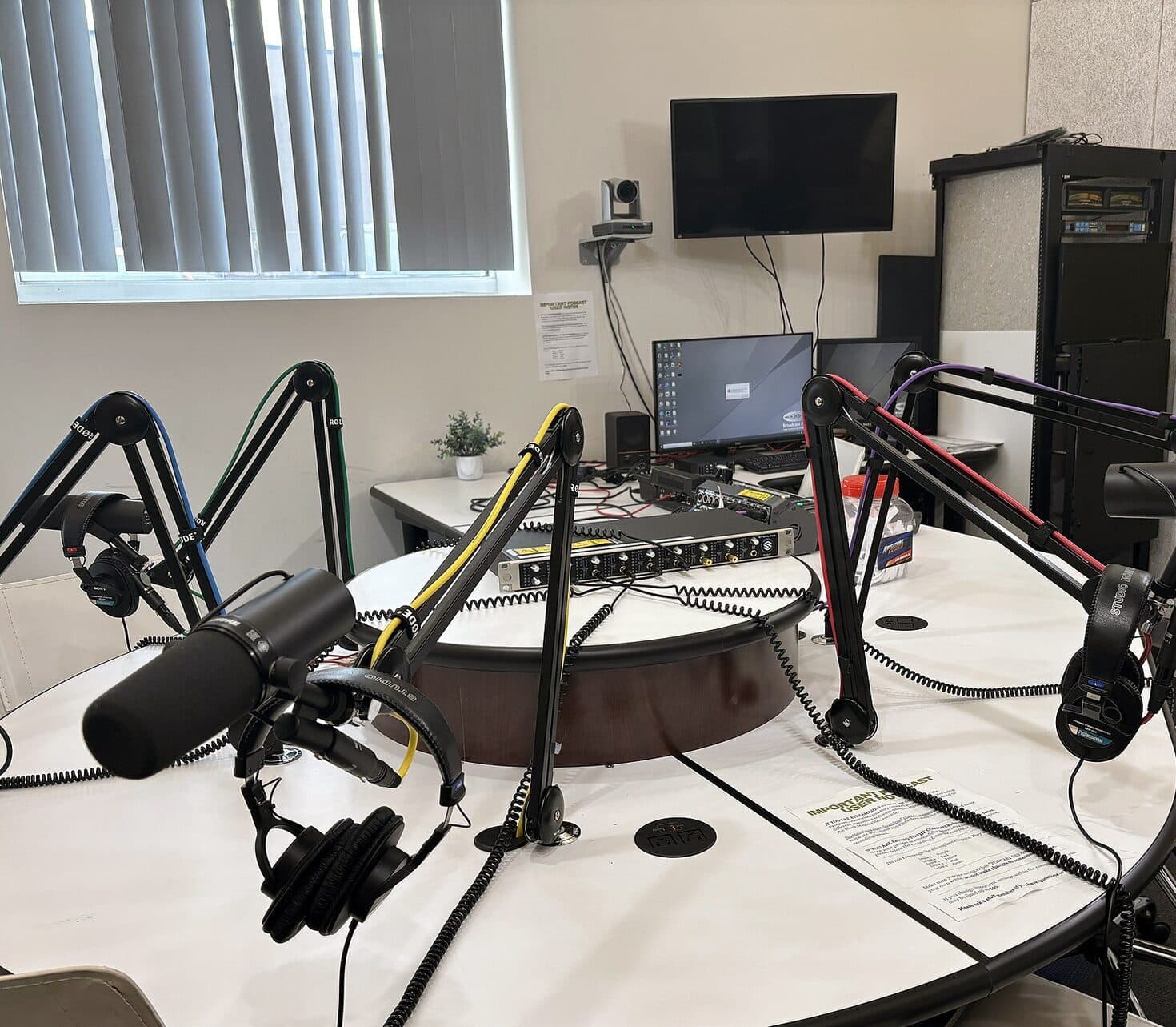 Microphones on boom arms around a round table in a podcast studio.